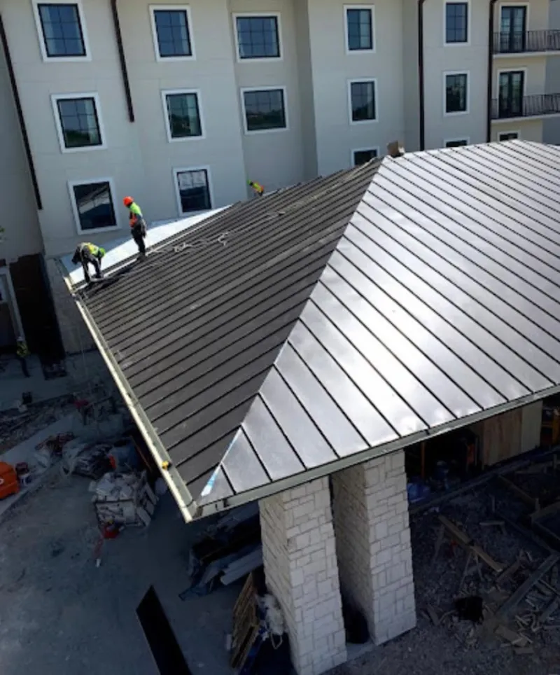 Crew installing standing seam metal roof panels on a commercial project in Colesville